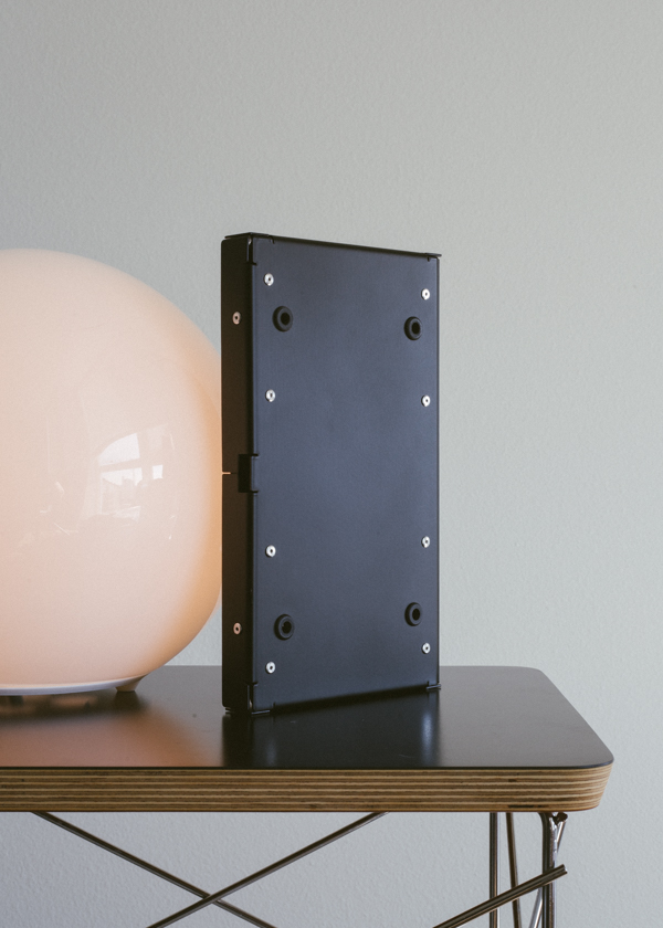 Keyboard standing on-end on a table next to a lamp, bottom side facing viewer